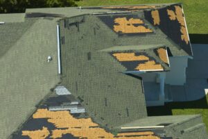 Wind damaged house roof with missing asphalt shingles after hurricane Ian in Florida.